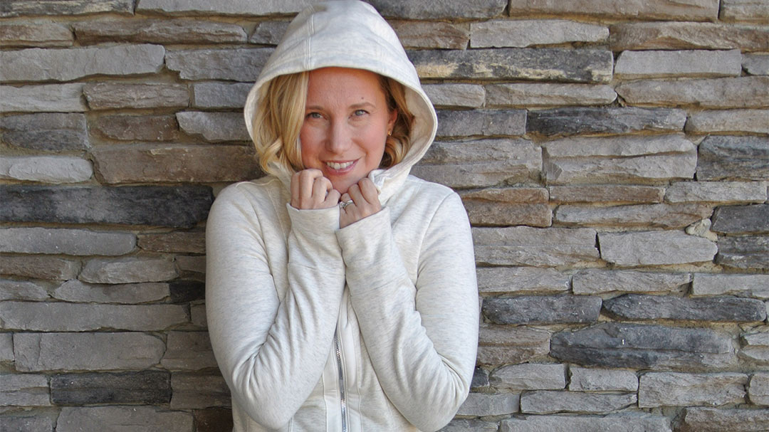 Laura in a light gray heather zip sweatshirt from Athleta with hood up