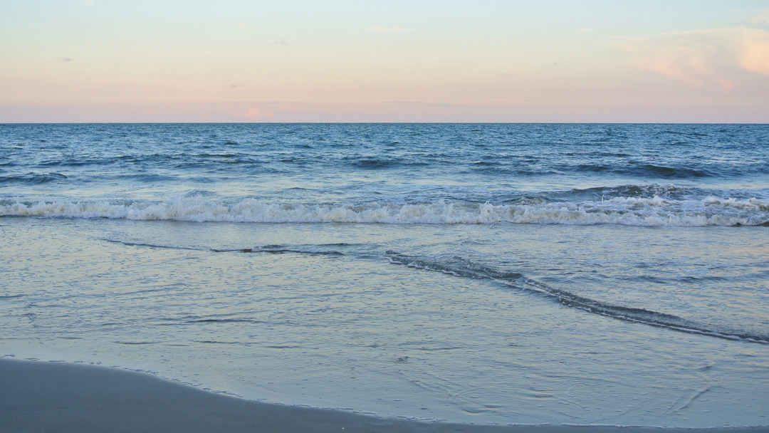 Sunset and waves crashing onto a beach