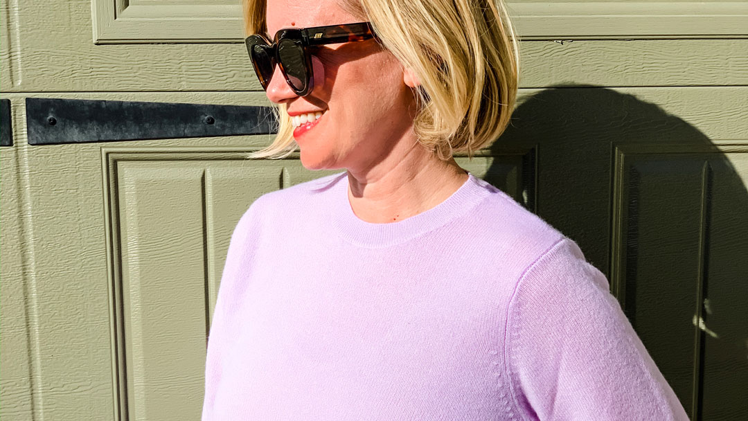 lavender sweater on woman in sunglasses standing in the sun